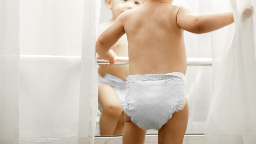 Criança de fralda no banheiro.