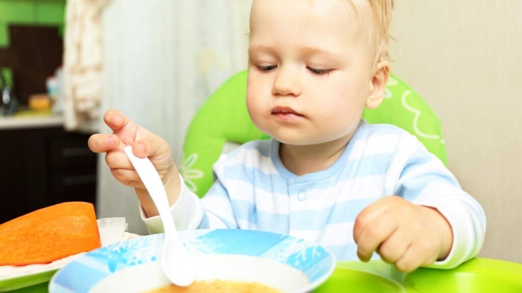 Crianca comendo na sua cadeira de alimentação