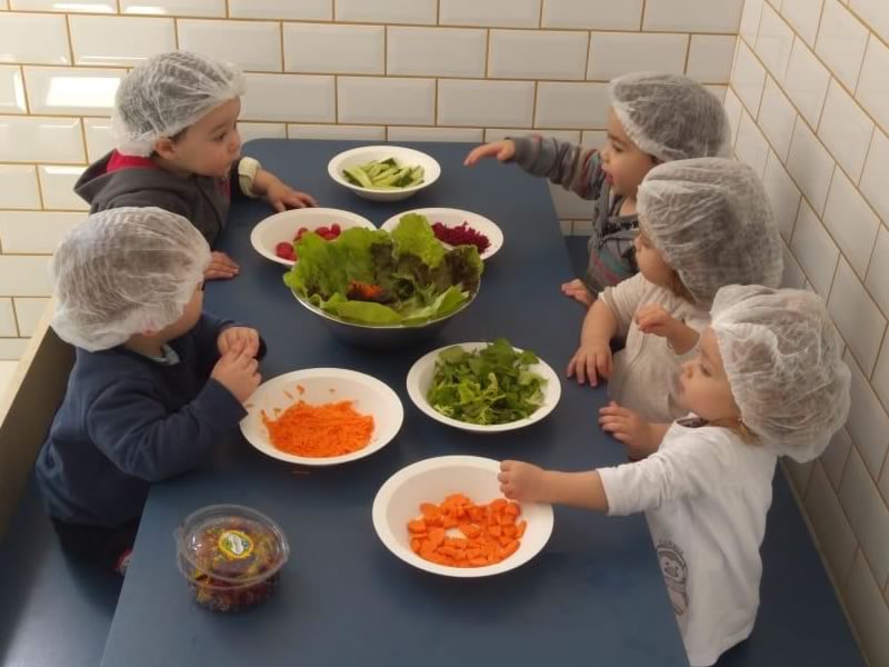 Crianças comendo salada na escola infantil