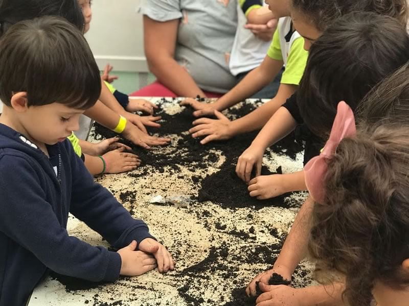 Crianças brincando com terra na escola infantil