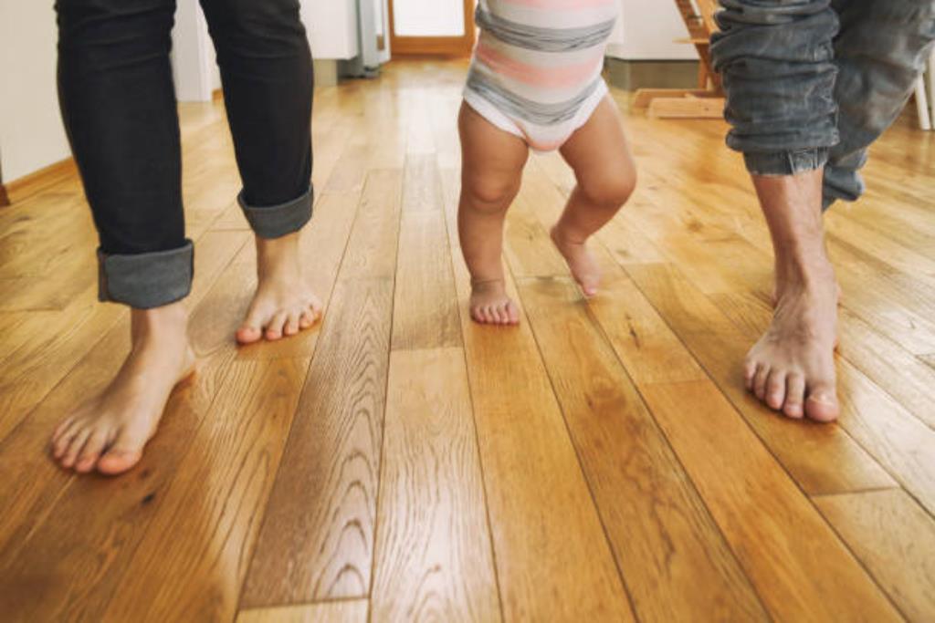 bebê com as pernas arqueadas dando os primeiros passos com os pais