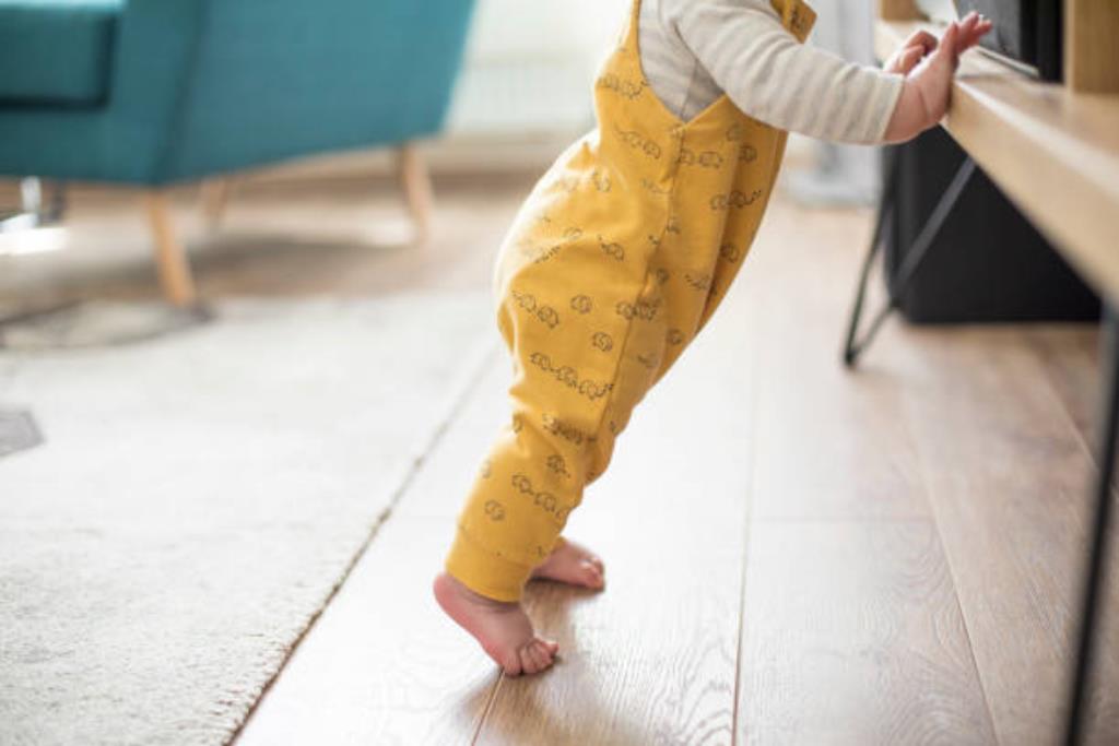 bebê em pé apoiado em móveis para aprender a andar sozinho