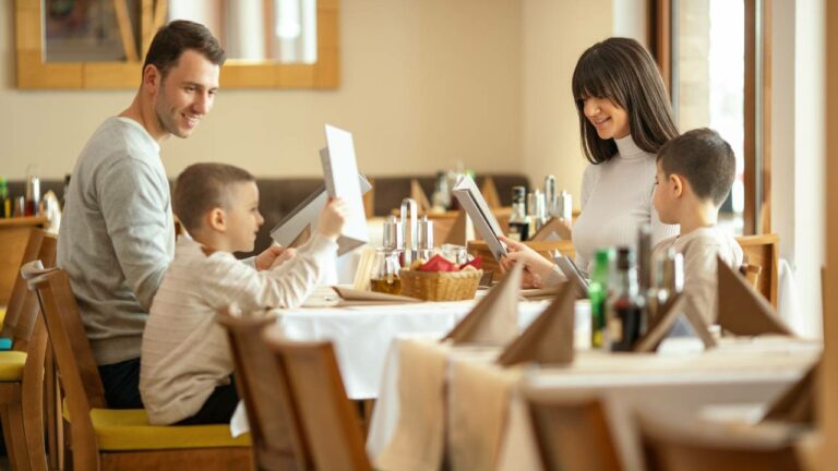 Família no restaurante e filhos vendo cardápio infantil.