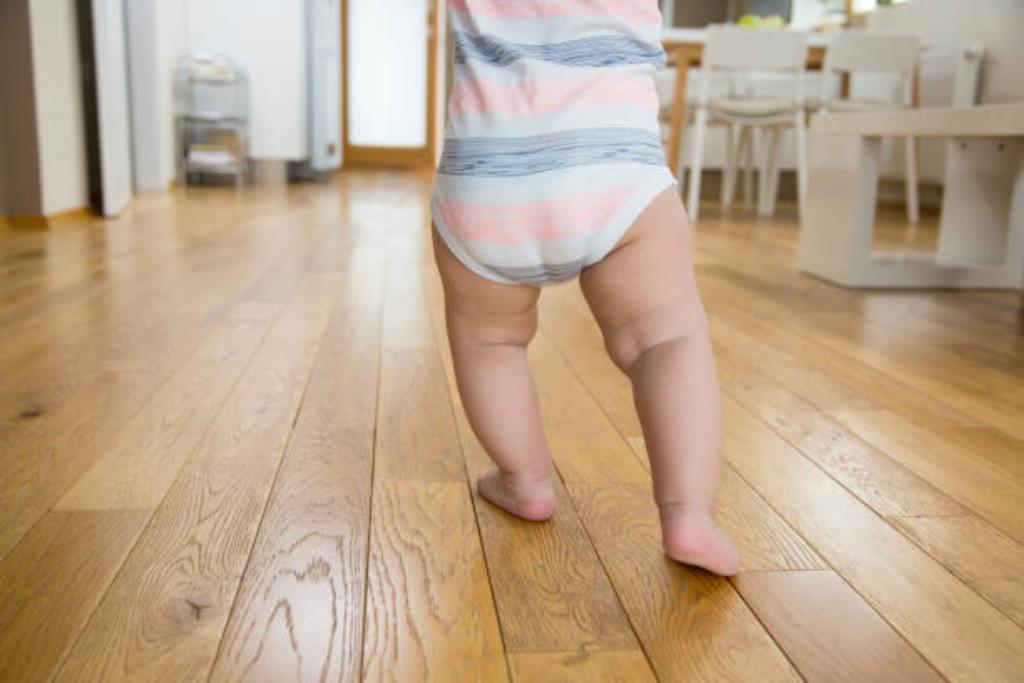 Bebê com as pernas arqueadas andando descalço.