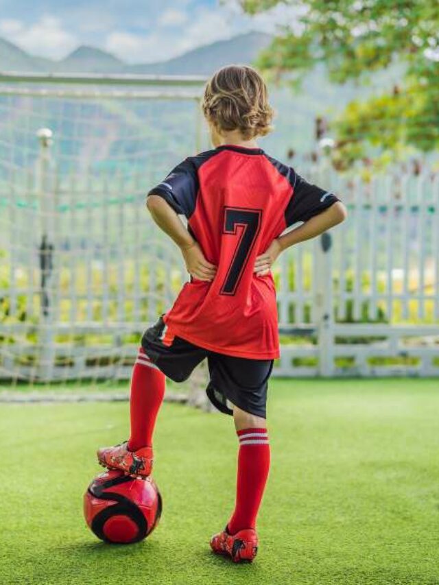 Garoto se preparando para cobrar falta em jogo de futebol infantil.