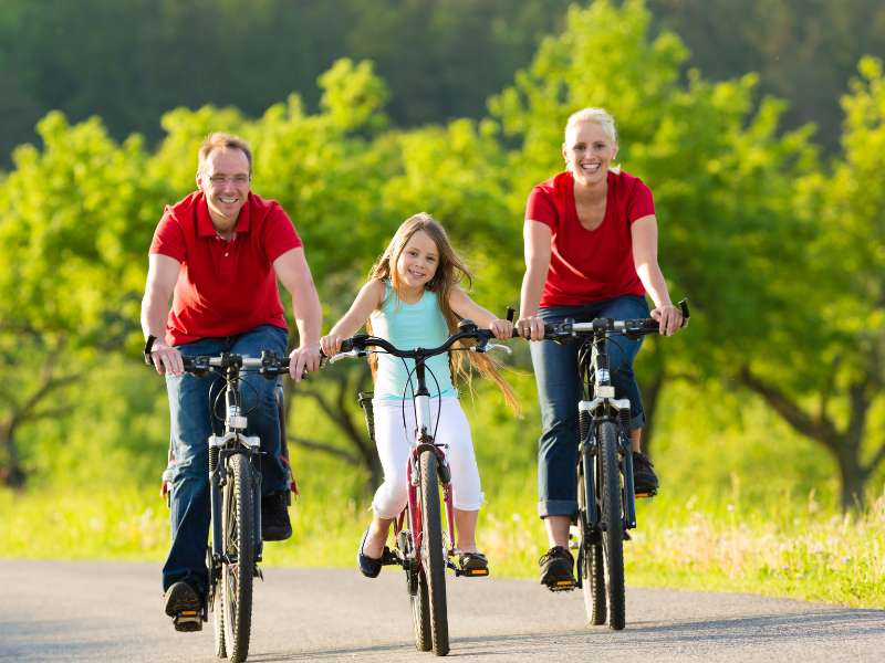Família no parque fazendo passeio de bicicleta.