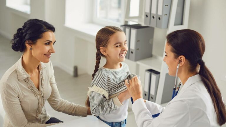 Pediatra examinando criança sorrindo na Vila Olimpia.
