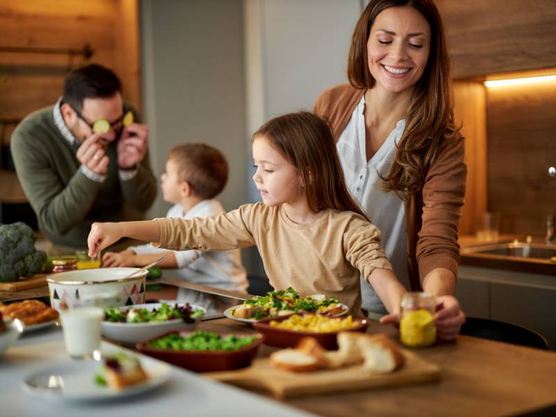 Crianças e pais cozinhando juntos.