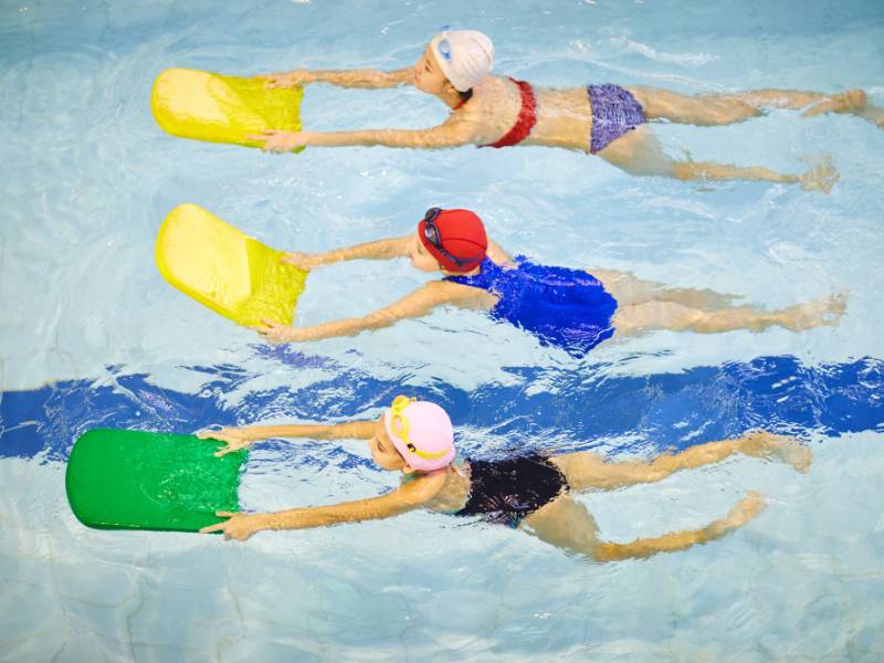 Crianças fazendo aula de natação como exercício físico. 