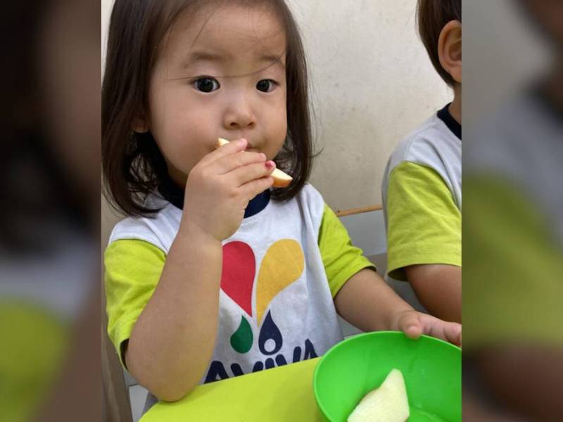 Criança comendo maça escola Aviva.