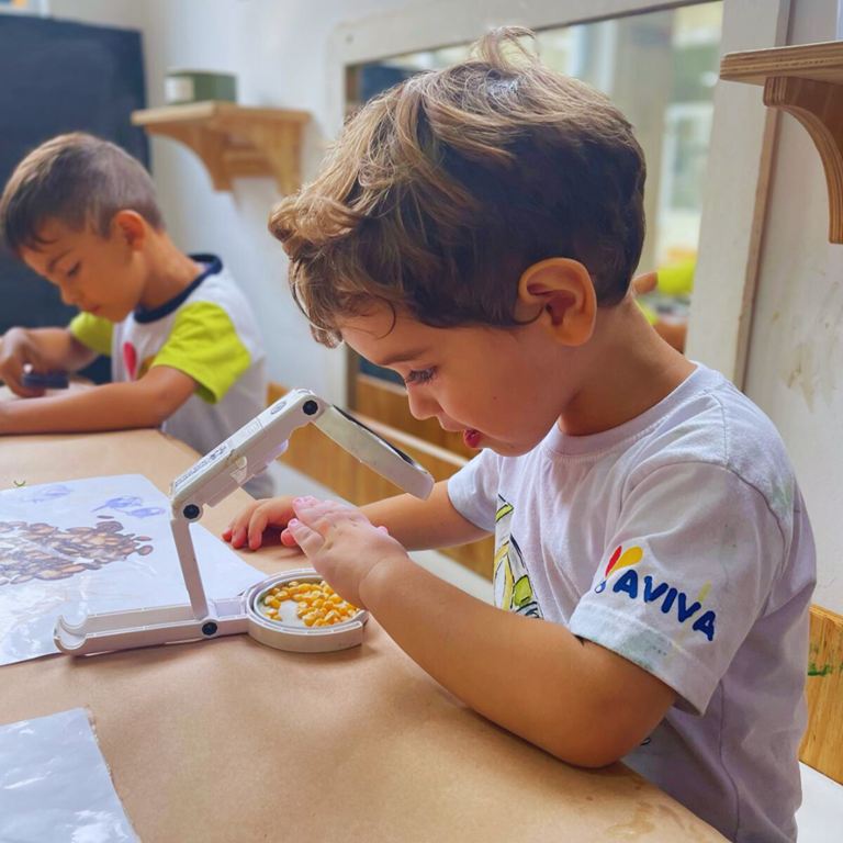 criança vendo microscópio na aviva escola infantil