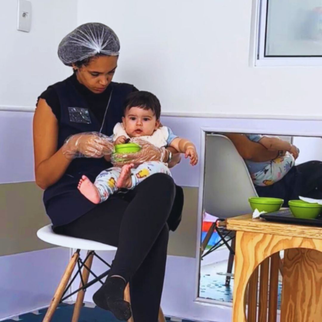 professora alimentando bebe no berçário da escola aviva