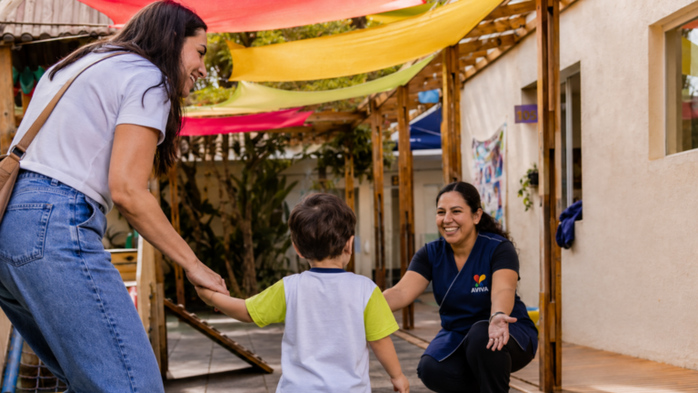 Criança é acolhida por professora na AVIVA durante o primeiro dia de adaptação escolar, em ambiente seguro, afetivo e preparado para a infância.