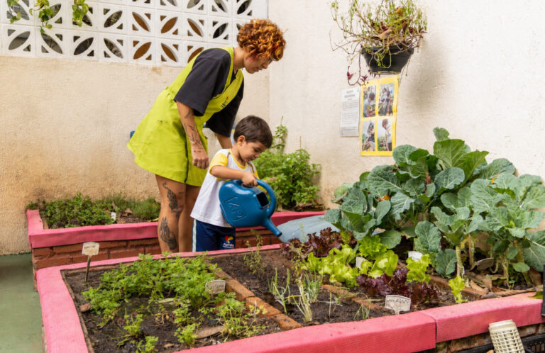 Criança da Educação Infantil da AVIVA cuidando da horta durante experiência de aprendizagem e contato com a natureza.